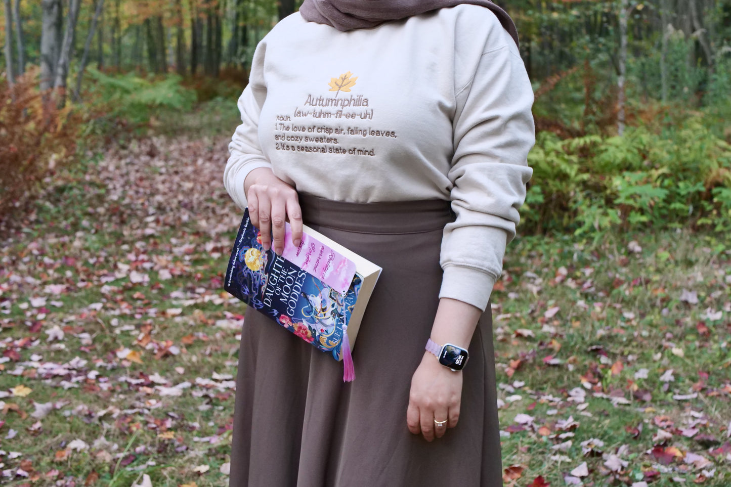 Person holding a book in a forest setting